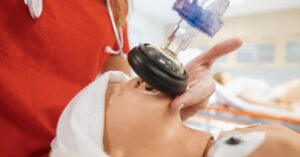 A healthcare provider uses a bag valve mask to ventilate an infant mannequin during NRP certification training.