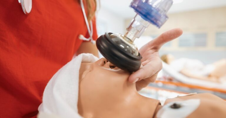 A healthcare provider uses a bag valve mask to ventilate an infant mannequin during NRP certification training.