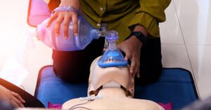 Healthcare provider practicing BVM ventilation techniques on a training mannequin during an AHA BLS certification course.
