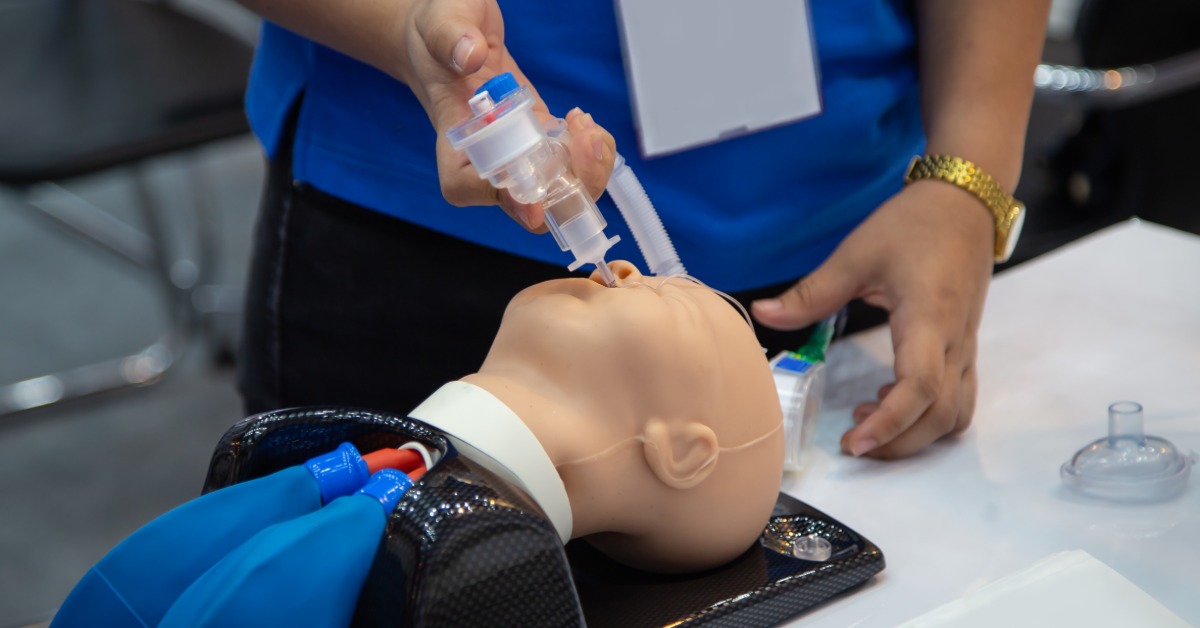 A healthcare provider practices endotracheal intubation on a pediatric airway mannequin during a resuscitation training course.